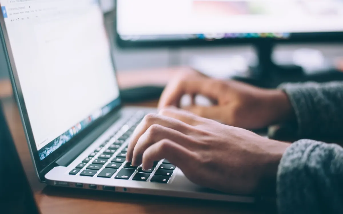 Hands typing on a laptop keyboard